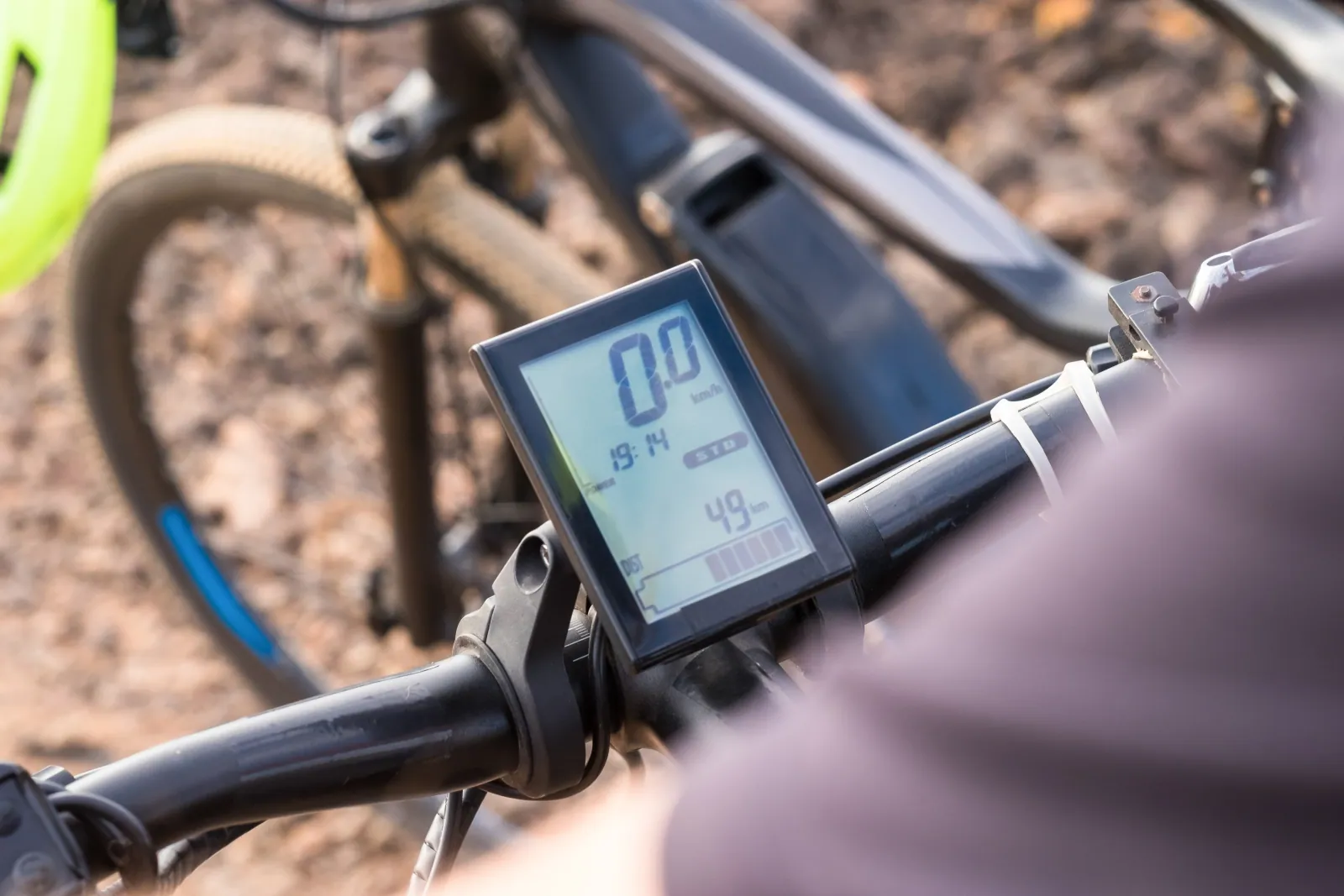 Bicycle computers arranged on a workshop bench: a GPS head unit on its mount, a basic non-GPS computer, and a heart rate sensor